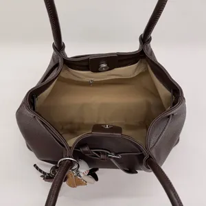 Vista interior del bolso tote de cuero marrón con cierre magnético y colgante de béisbol