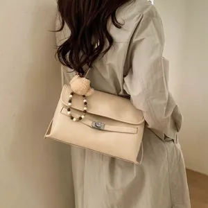 Dettaglio borsa tote beige in pelle PU con chiusura a scatto e ciondolo a orsetto