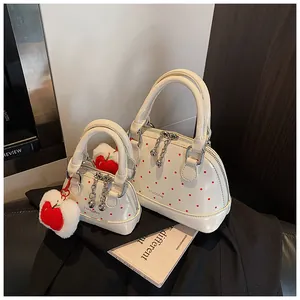 Detailed macro view of white patent leather shell bag set with red polka dot pattern and charm