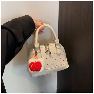 Detail of white shell handbag with red dots and creative plush apple charm accessory