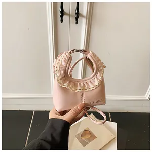 Detail of pink faux leather bag featuring delicate lace trim and HELAHE branding