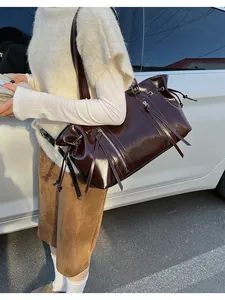 Close-up of vintage brown gloss leather tote with long tassel zipper and drawstring detail