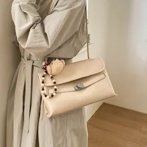 Dettaglio della borsa tote beige crema con chiusura a rotazione argento e ciondolo orso