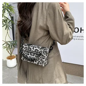 Detail of trendy leopard print crossbody bag featuring a chunky black resin chain strap