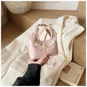 Close-up of pink fashion bag featuring lace-wrapped handle and brand logo details