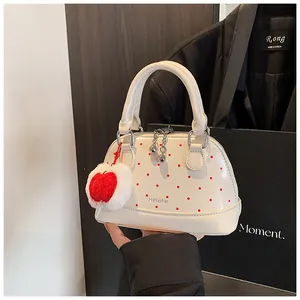 Detail of cream patent leather mini bag with red dots and plush apple charm