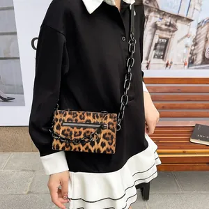 Detail of leopard print crossbody bag with chunky black chain strap and zipper pocket