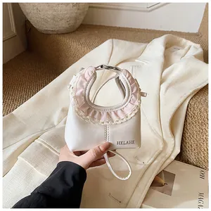 Detail of a white faux leather tote with pink lace ruffles and circular handles