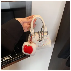 Detail of white mini handbag with red polka dots and apple-shaped plush charm