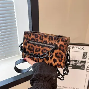 Close-up of leopard print handbag featuring a black chunky chain and smooth zipper detail