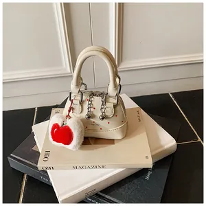 Chic mini handbag with red polka dots and apple plush charm on a pile of books