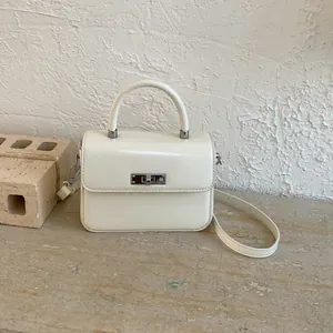 Elegante cremefarbene quadratische Handtasche mit Drehverschluss und rundem Griff