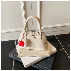 Detailed shot of cream polka dot handbag with silver zipper and red apple plush charm