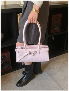 Pink leather handbag with belt buckle detail and thin handles shown in a lifestyle setting