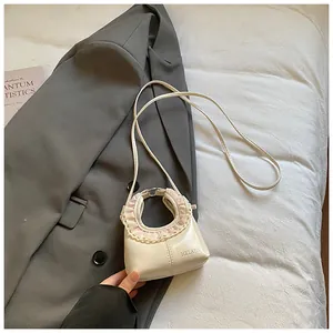 Close-up of cream PU leather handbag featuring delicate pink lace trim and brand logo