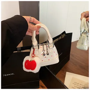 Detail of white polka dot mini handbag featuring a red apple plush charm and Hehehe print