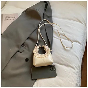 Detail of cream mini shoulder bag with lace trim and brand logo in a lifestyle setting