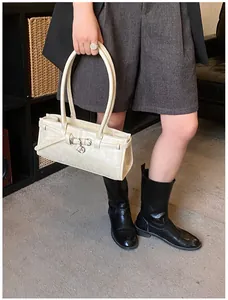 Chic cream white shoulder bag with silver buckle detail worn by a model in casual outfit