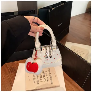 Detail of white mini handbag with red polka dots and a cute plush apple charm attachment