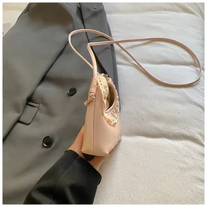 Detail of lace trim on a soft pink underarm bag with pleated edge and knotted strap