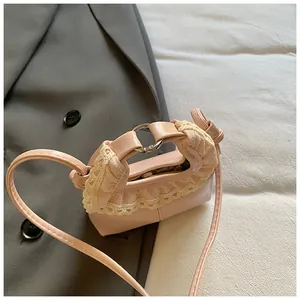 Close-up of pink mini crossbody bag with delicate lace trim and metal ring handle detail