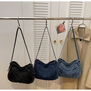 Trois grands sacs à bandoulière en denim noir et bleu suspendus sur des crochets