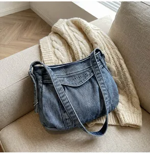 Détail d'un sac cabas en jean bleu avec texte brodé et design plissé tendance
