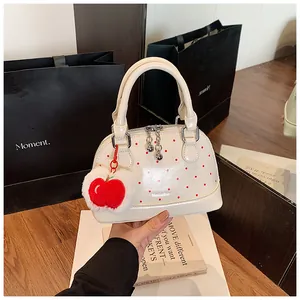 Detail of cream patent shell bag with red polka dots and apple plush charm decor