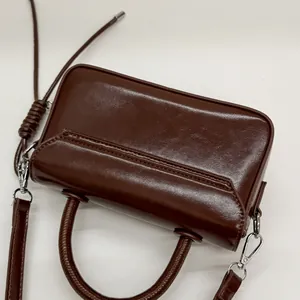 Deep brown glossy leather handbag detail showing smooth texture and silver metal buckles