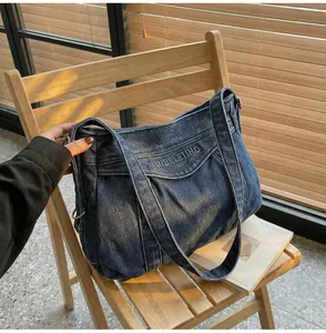 Détail du sac en jean bleu avec broderie JUBELETING posé sur une chaise en bois