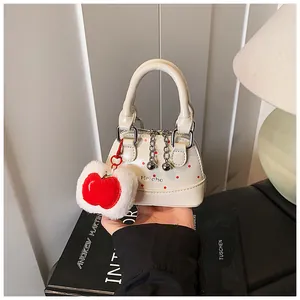 Close-up of mini white PU handbag with red polka dots and plush apple charm detail