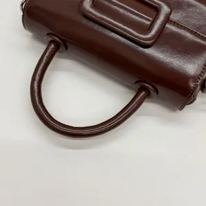 Detailed macro view of caramel brown leather handbag with reinforced round handle and stitching