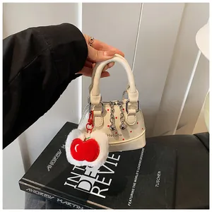 Detailed view of mini white polka dot handbag with a red apple charm and Helahe logo