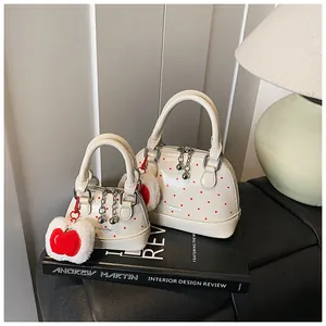 Detail of cream polka dot shell bags with red apple charms on design books