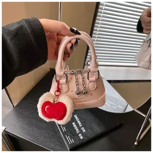 Detail of pink polka dot shell bag with plush apple charm and silver chain strap