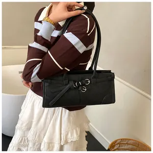 Detail of black leather underarm bag with decorative straps and silver buckles