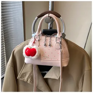 Pink shell handbag with red polka dots and a red plush apple charm detail