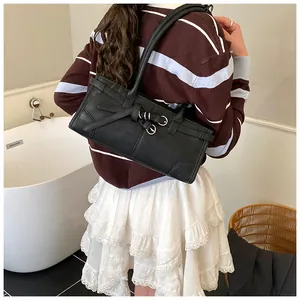 Detail of black leather shoulder bag with silver buckles worn over the shoulder