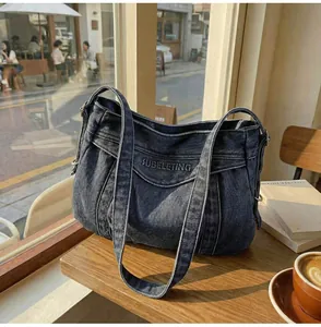 Détail d'un sac cabas en jean rétro avec broderie de lettres 3D sur une table de café