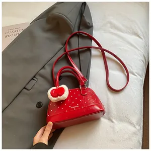 Detail view of red polka dot shell bag on grey suit with plush heart charm