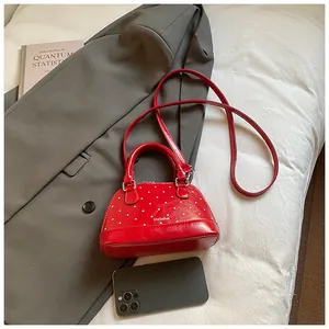 Detailed top view of red shell bag with white polka dots and golden metal logo