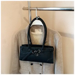 Close-up of black leather square shoulder bag with silver rings and strap detail on a blazer