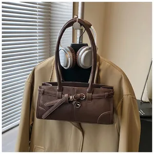 Detailed view of a brown vintage tote bag with metal buckles on a khaki trench coat