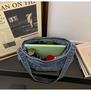 Intérieur spacieux du sac bandoulière en jean bleu avec téléphone, tablette et cosmétiques