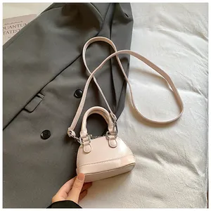 Macro detail of a light pink shell-shaped mini handbag on a textured grey fabric background