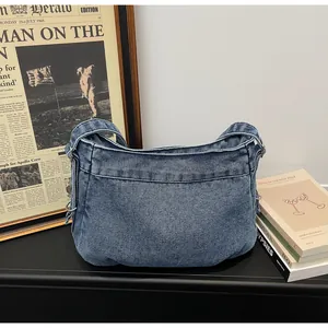 Détail du sac cabas en jean bleu montrant la texture délavée et les anneaux métalliques
