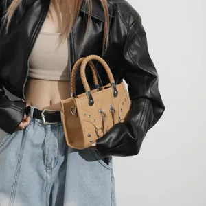 Camel leather motorcycle bag with silver rivets and woven handles on a stylish model