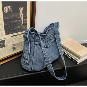Détail du sac bandoulière en denim bleu montrant la texture vintage et la broderie