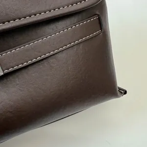 Dettaglio borsa tote in pelle marrone con cuciture bianche a contrasto e fibbia argentata