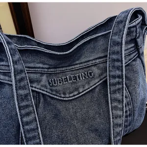 Vue détaillée du sac cabas en denim bleu foncé avec broderie SUBELETING et texture
